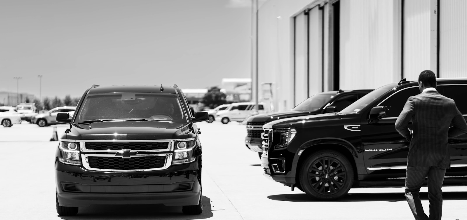 Chauffeur standing beside black luxury SUVs